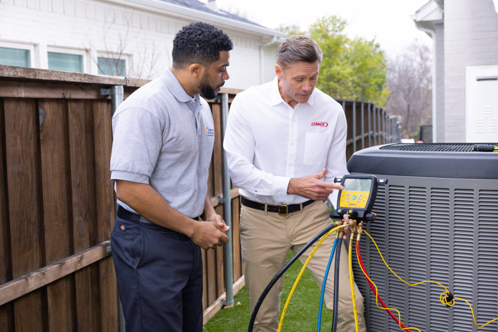 Nuvo HVAC technician repairing AC unit in an Oak Lawn, TX historic home on a sunny afternoon