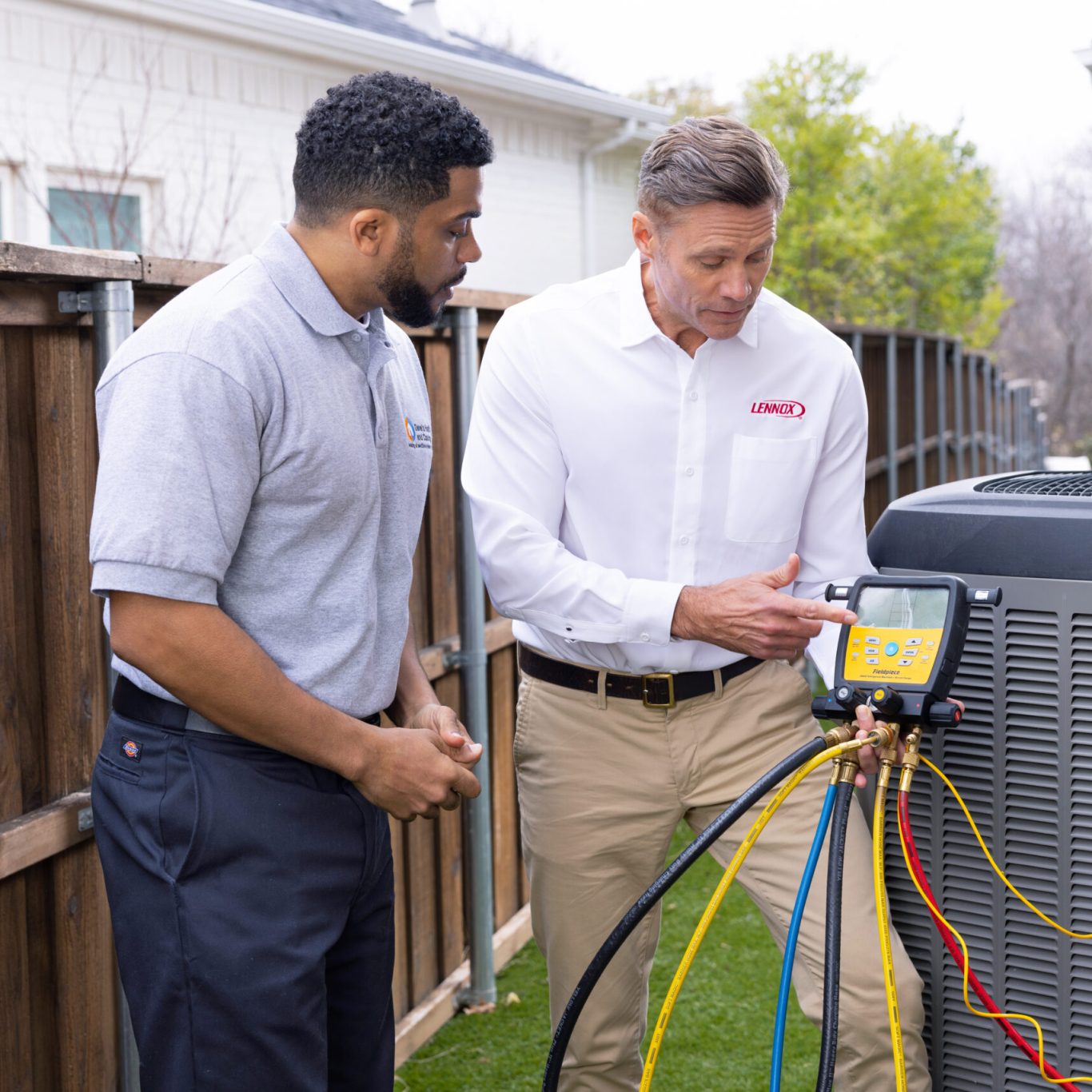 Nuvo HVAC technician repairing AC unit in an Oak Lawn, TX historic home on a sunny afternoon